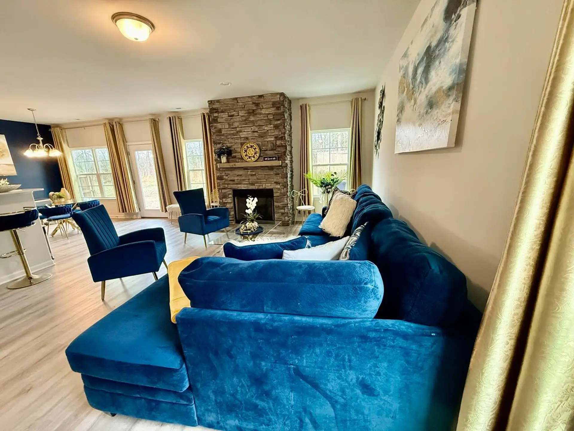 Cozy living room with blue sofa, fireplace, and bright natural light.