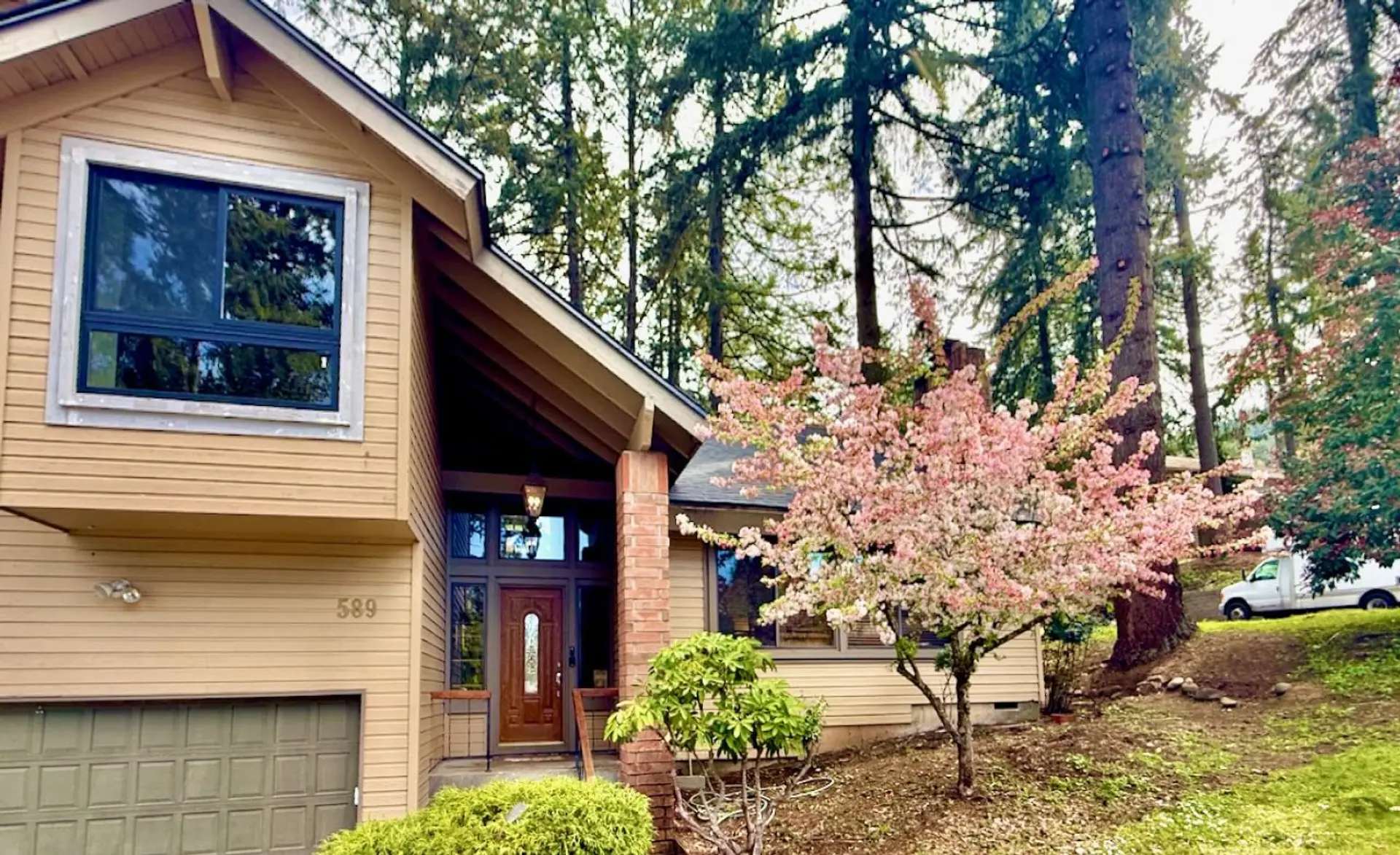 Large home with vaulted ceilings surrounded by tall trees.