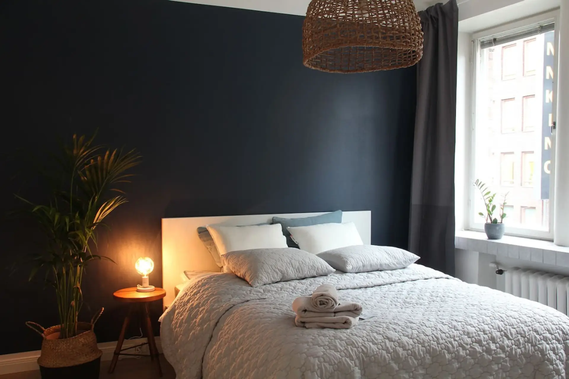 Cozy bedroom featuring a large double bed, warm lights, plants and a nice view of Helsinki