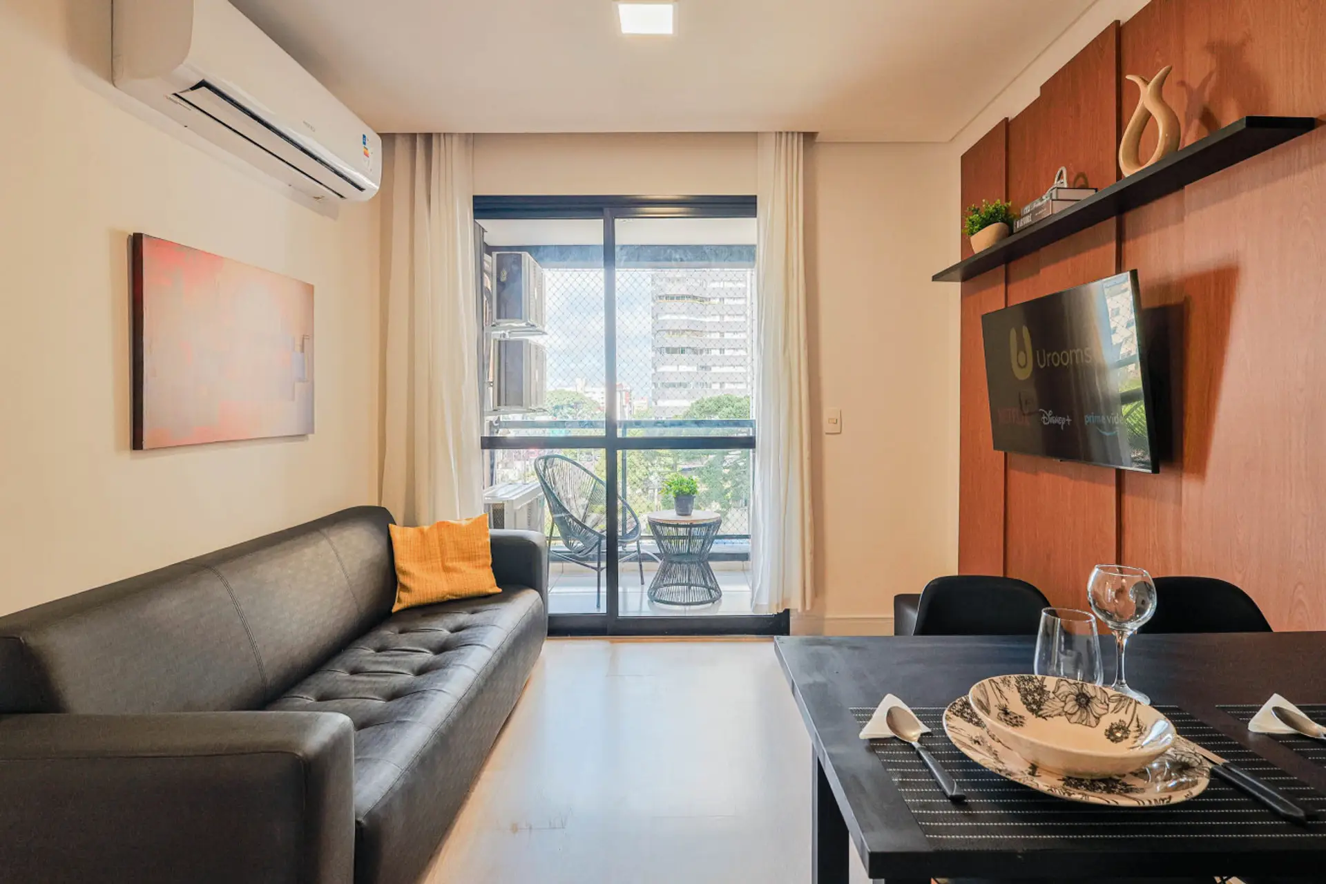 Sala de estar com sofá, TV e sacada