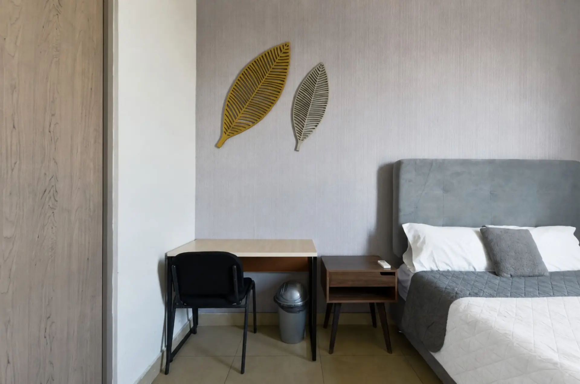 Habitación A con cama Queen Size, escritorio, clóset y vista a la ciudad. Incluye colchas, almohadas y cojines para un descanso cómodo y acogedor.