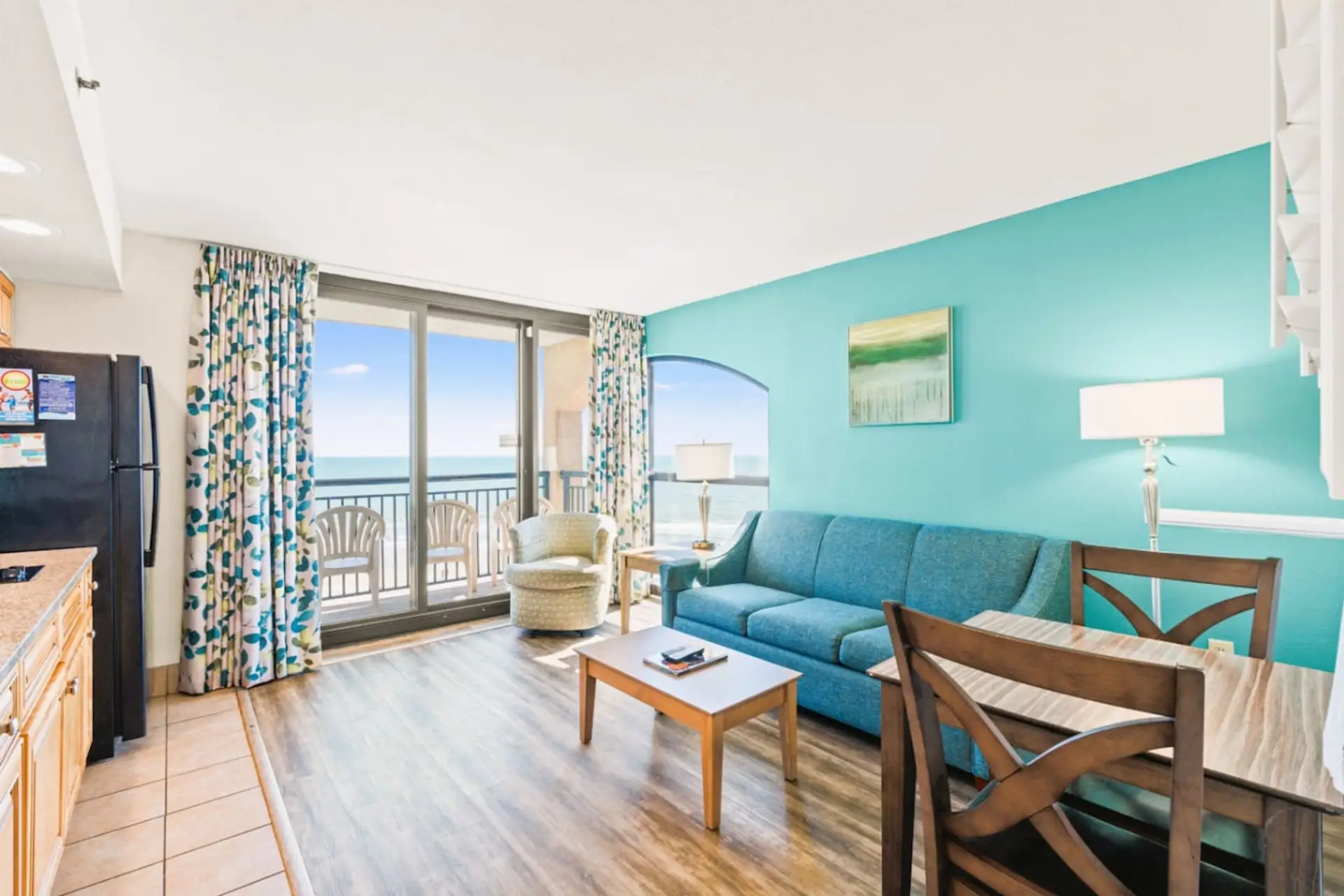 Floor-to-ceiling windows open onto a private balcony in this oceanfront living room, catching rare sunrise and sunset views.