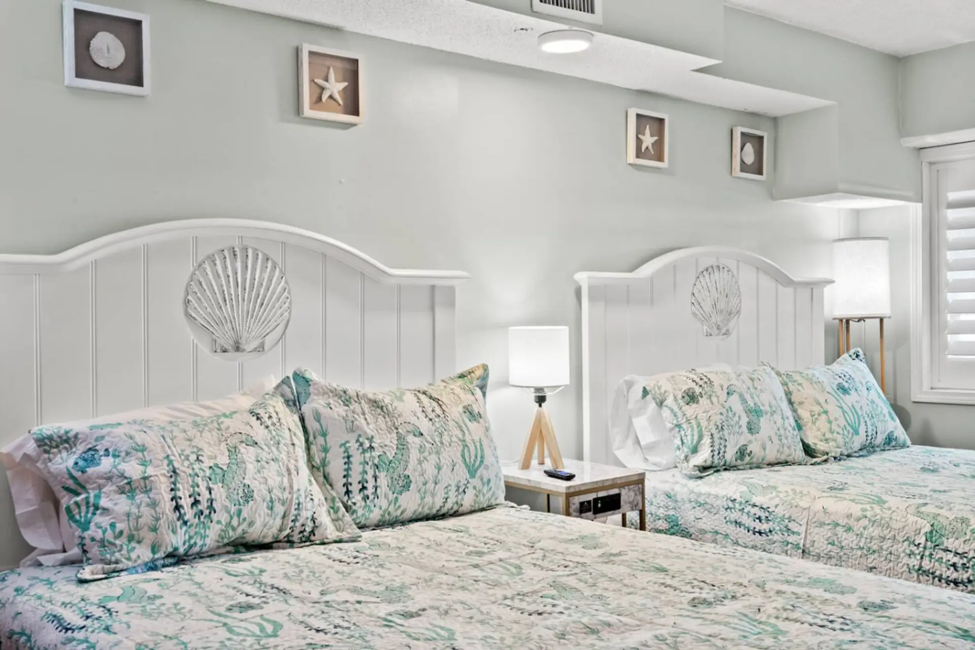 Two plush queen beds dressed in crisp hotel-style linens fill this relaxing coastal bedroom.