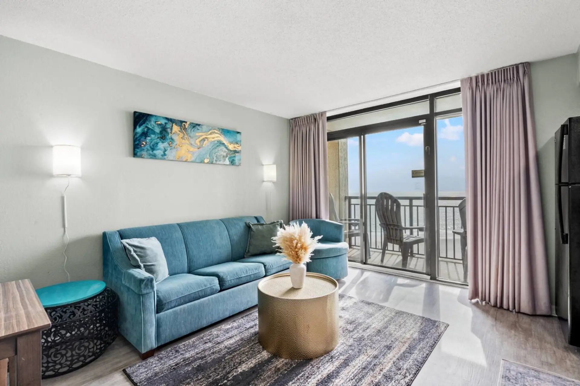 Bright, beach-themed living room with a full-size sofa and queen sleeper, filled with natural light.