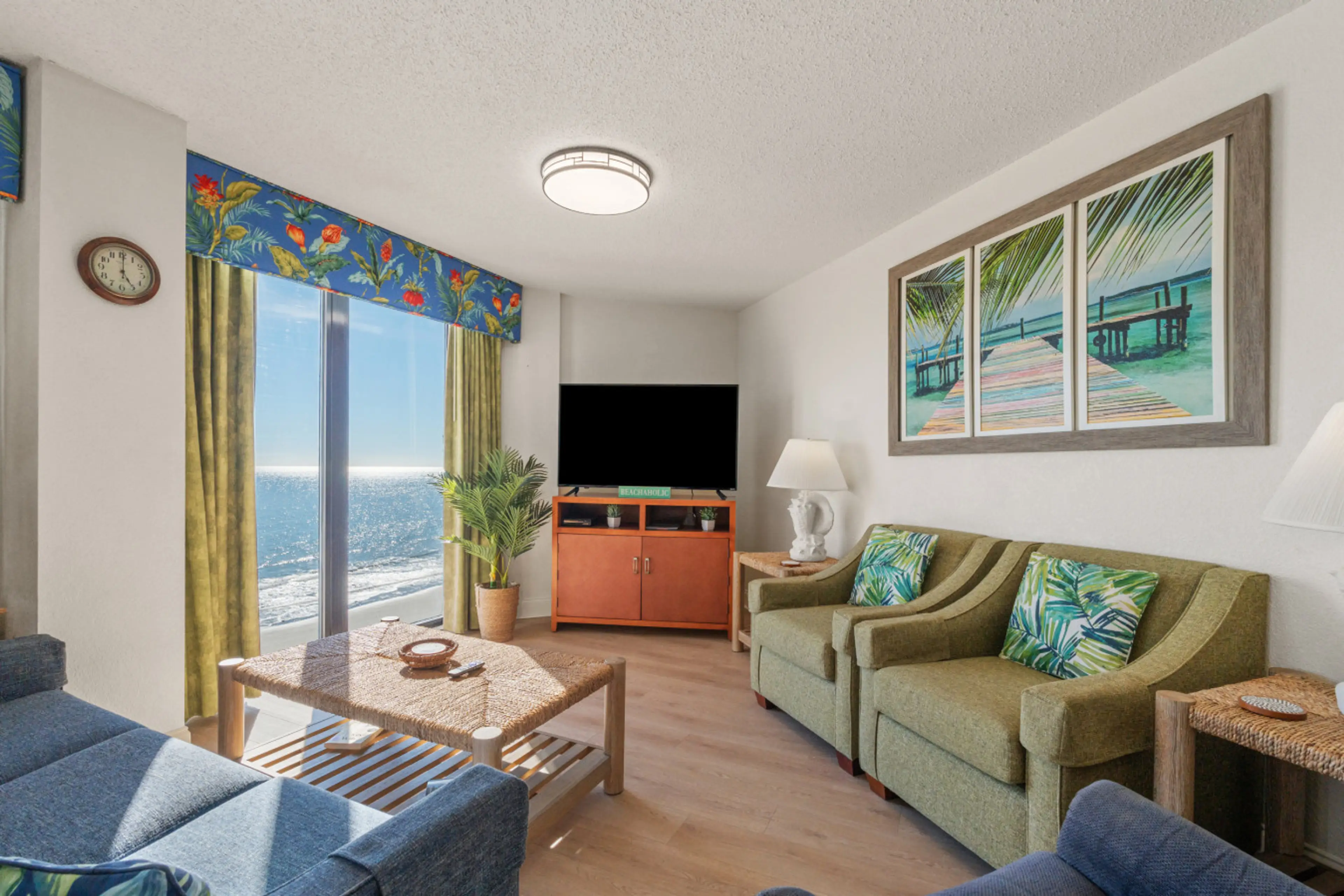 Spacious oceanfront living room with seating for 6, a sleeper sofa, and a 50" Smart TV. Floor-to-ceiling windows provide stunning direct oceanfront views and fill the space with natural light.