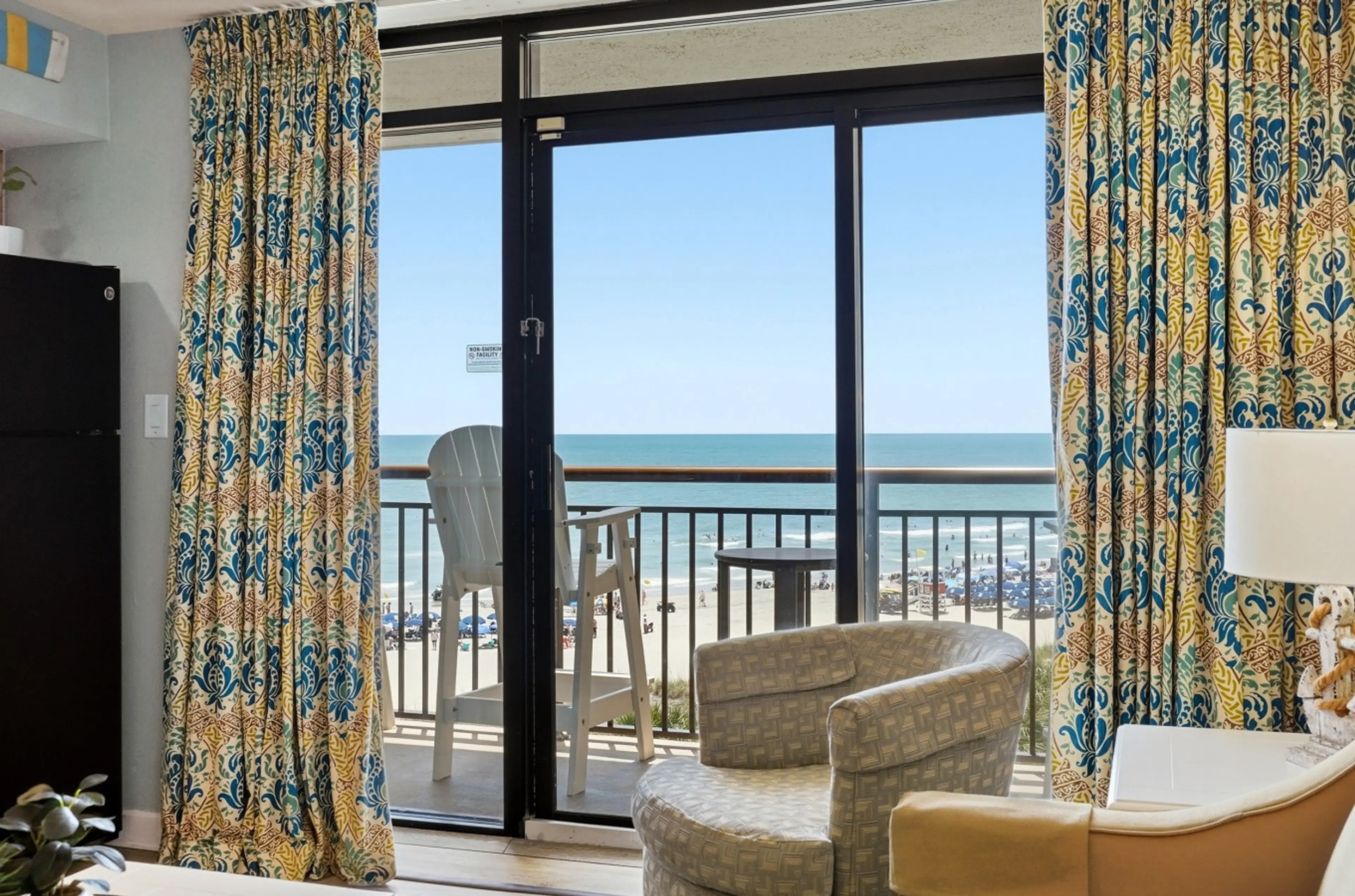 Oceanfront living room with breathtaking direct oceanfront views of the Atlantic, Beach Cove Resort's tropical pools, hot tubs, lazy river, fountains, and poolside beach bar. Relax in comfort while enjoying unforgettable Myrtle Beach oceanfront scenery.