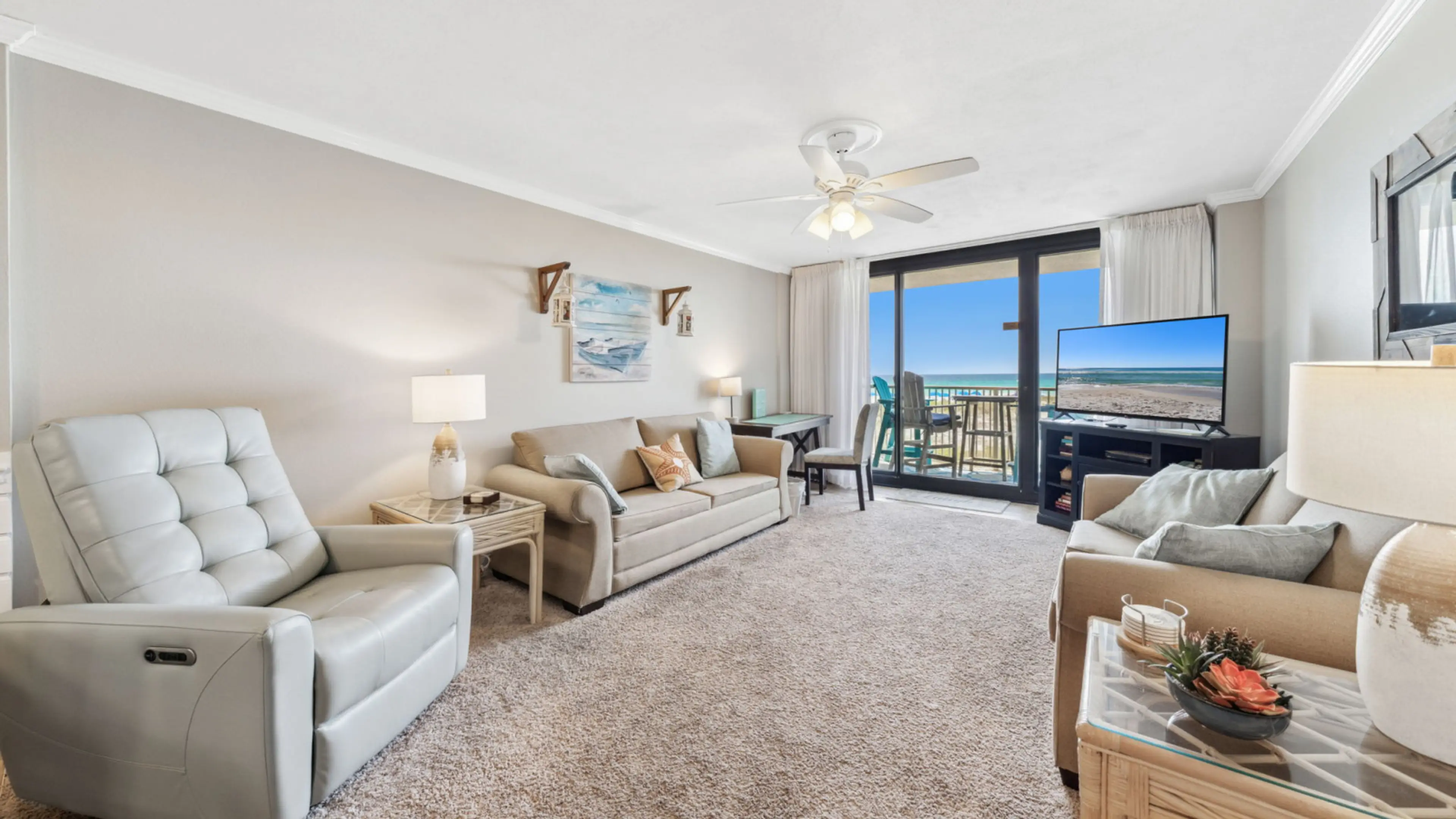 This bright and inviting living room features plush seating, coastal décor, and a large flat-screen TV, all centered around stunning beach views through sliding glass doors. Step outside to the private balcony and enjoy the sights and sounds of the Gulf j
