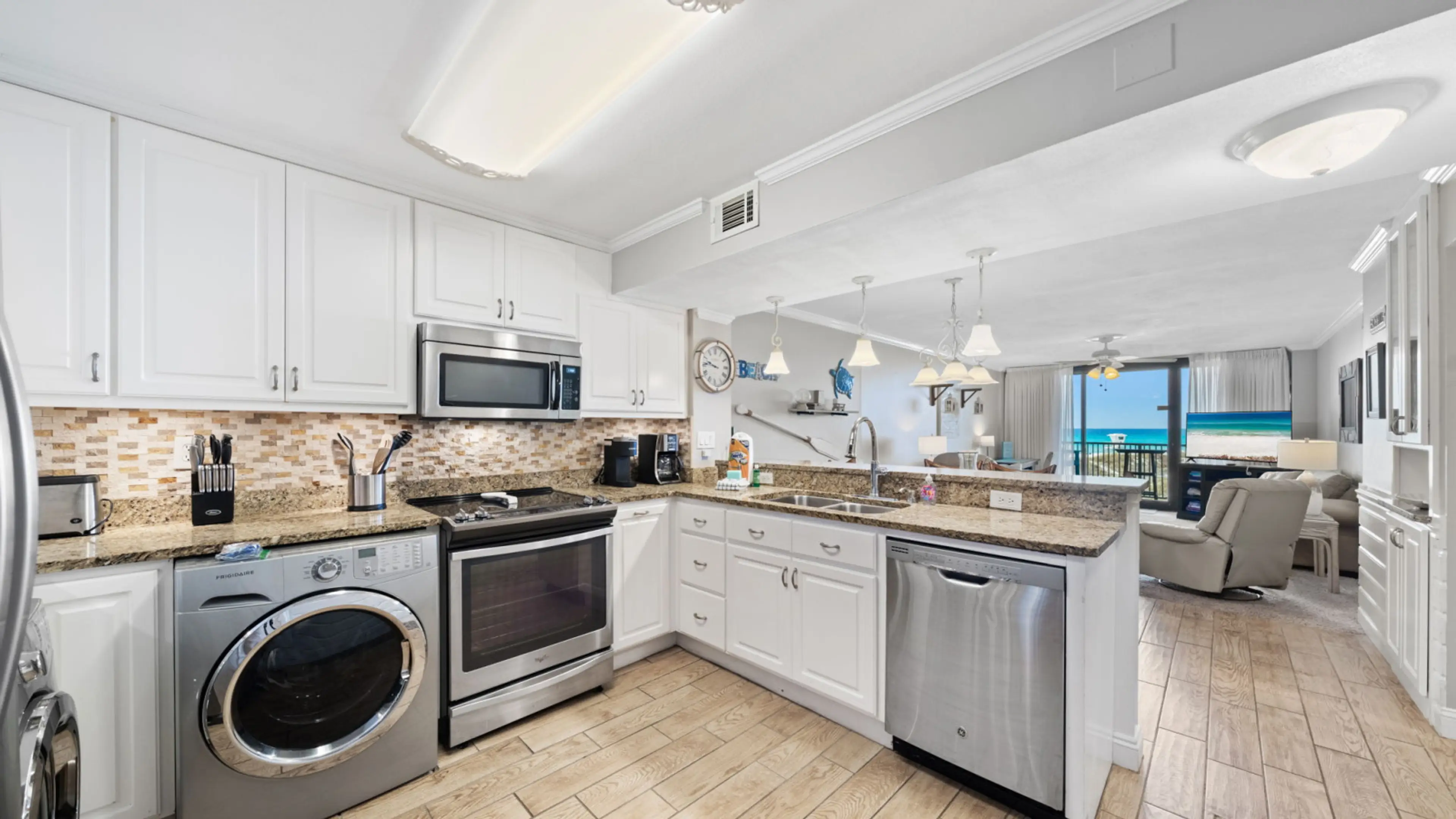 This fully equipped kitchen features stainless steel appliances, granite countertops, a tile backsplash, and in-unit laundry, all set in an open layout that flows seamlessly into the living area. Enjoy ocean views while you cook, with natural light stream