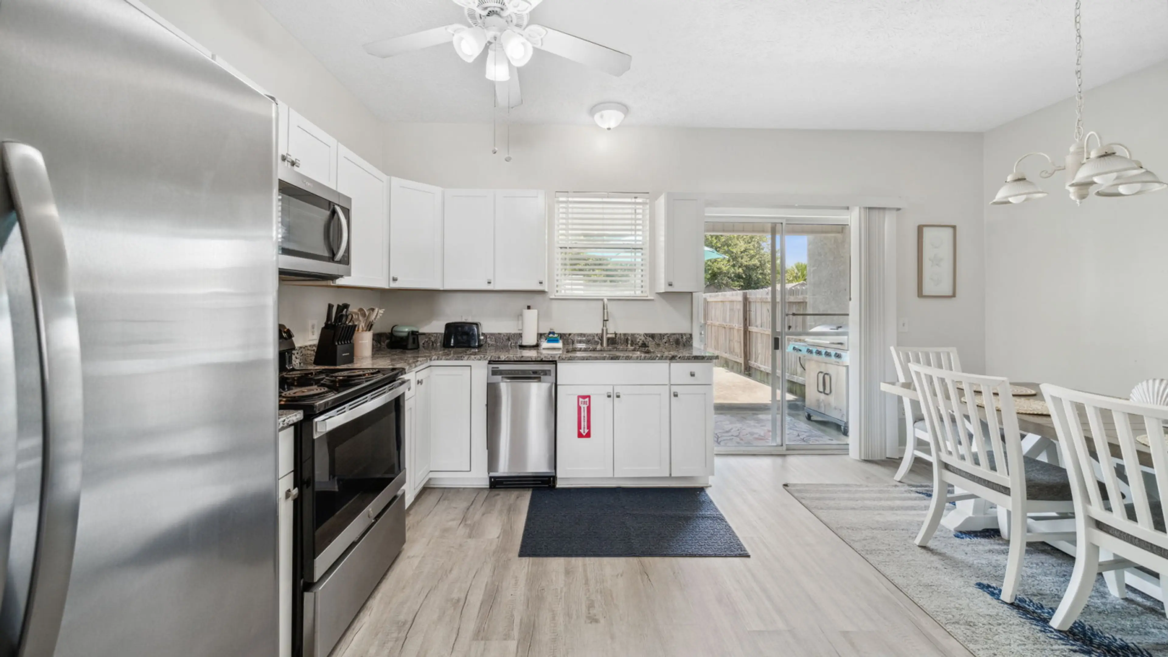 This open-concept kitchen and dining area is both stylish and functional. Outfitted with sleek stainless steel appliances, granite countertops, and crisp white cabinetry, the kitchen is perfect for preparing meals with ease. The adjacent dining space feat