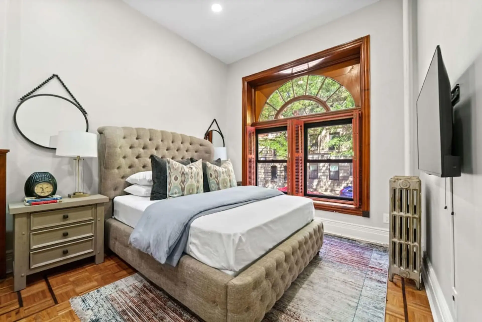 The master bedroom is elegant, with a queen-size bed and a beautiful headboard. A wide window lets in plenty of natural light, making the room warm and inviting. It's a well-designed space for a peaceful night's sleep.