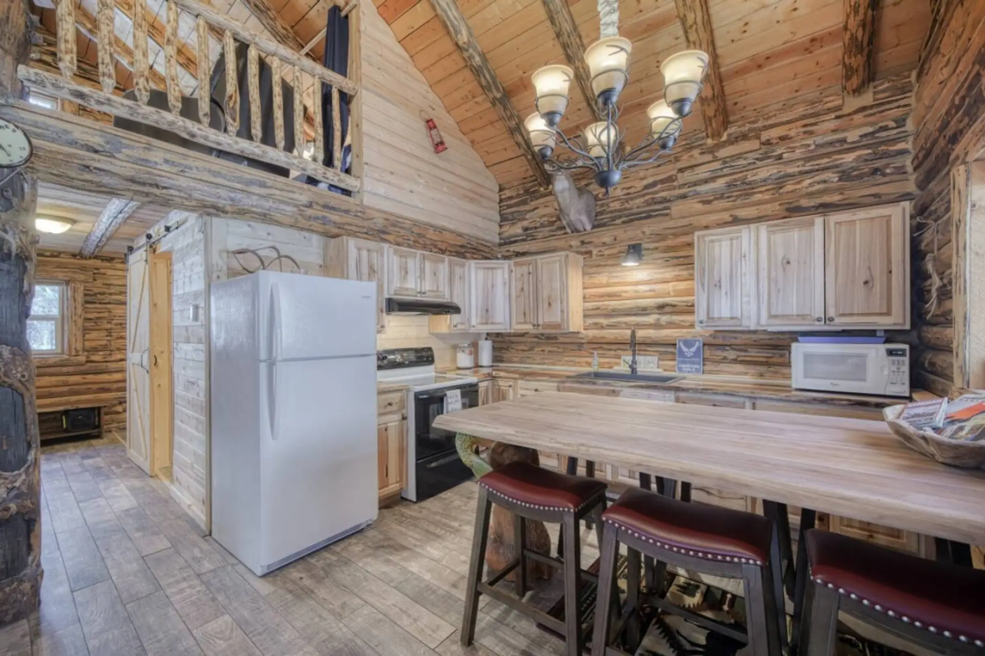 Rustic kitchen and dining area with large island, full-size appliances, and seating for group meals.