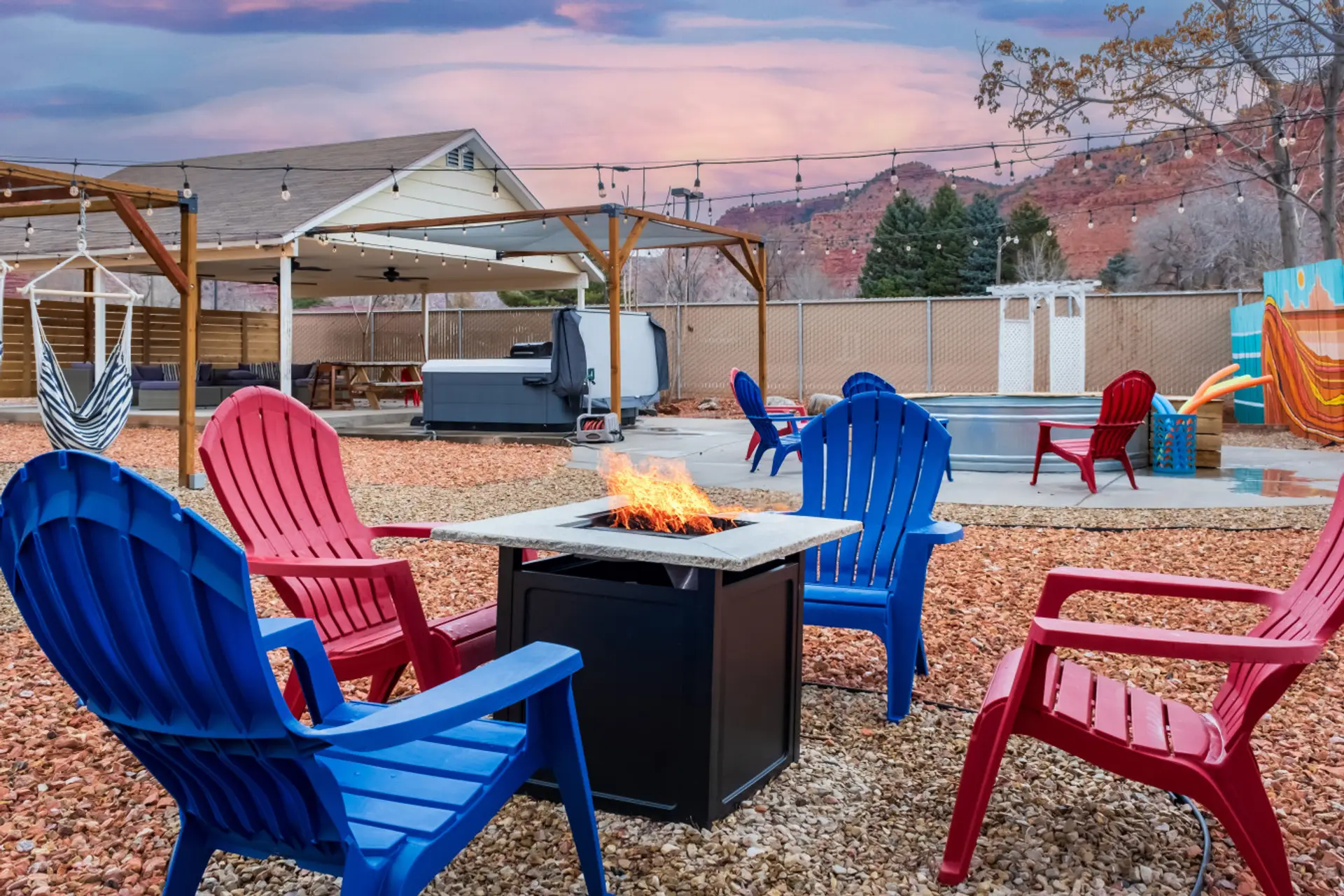 Fire pit seating area with pergola, string lights, and nearby plunge pool.