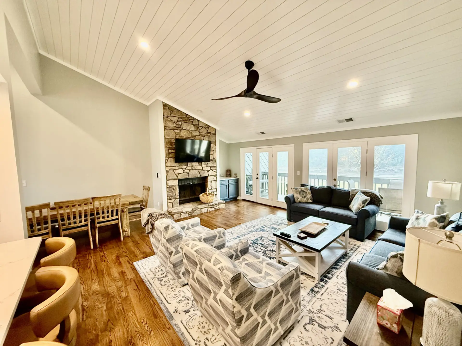 Family room seating area. Brand new furniture including couch and two swivel barrel chairs. 60” smart TV over the fireplace.  Doors open up to upper level balcony with breathtaking views of Lake Lure and the surrounding mountains.