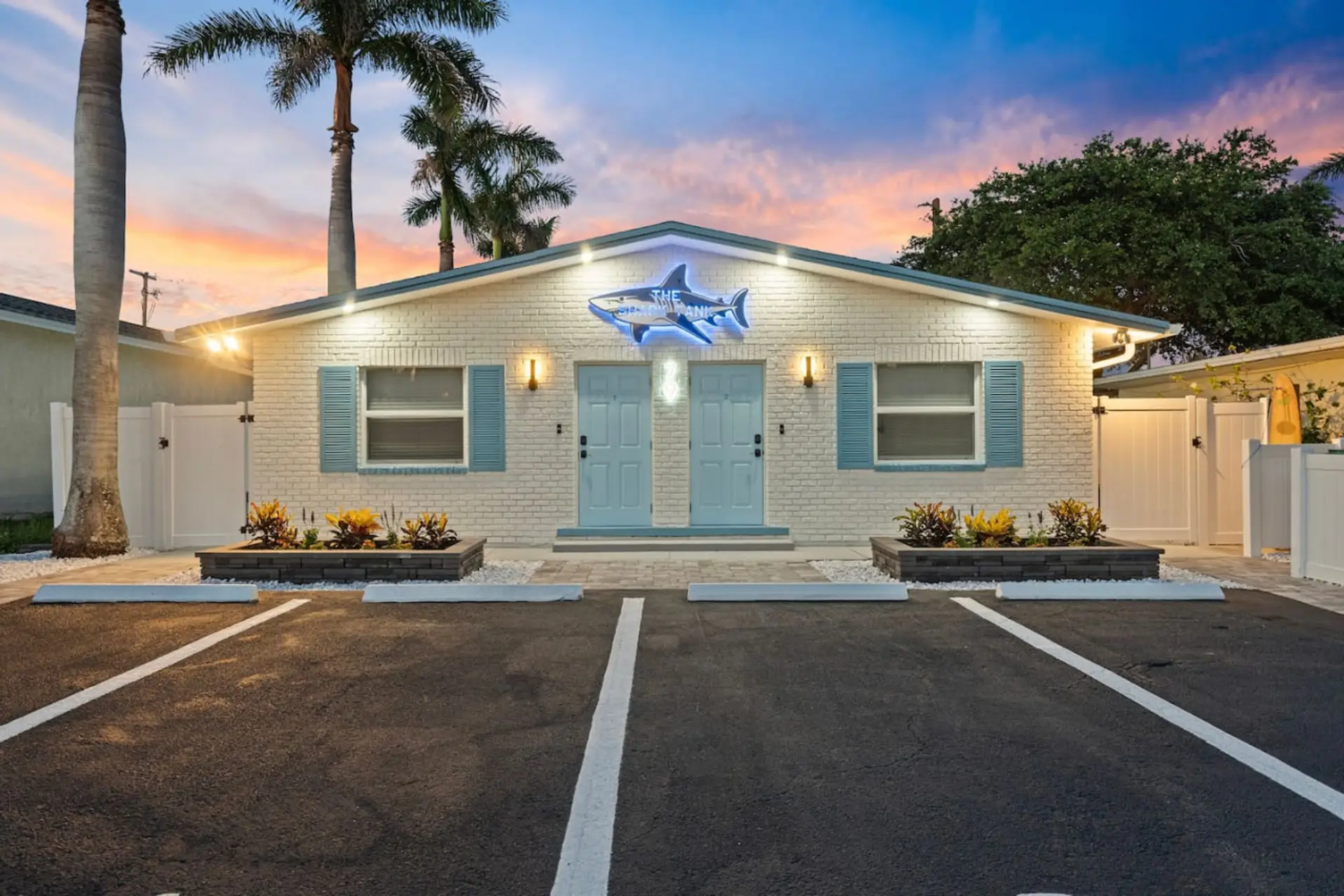 Cocoa Beach front exterior with twin entry doors, signature shark signage, and private parking—welcoming, tropical, and coastal.