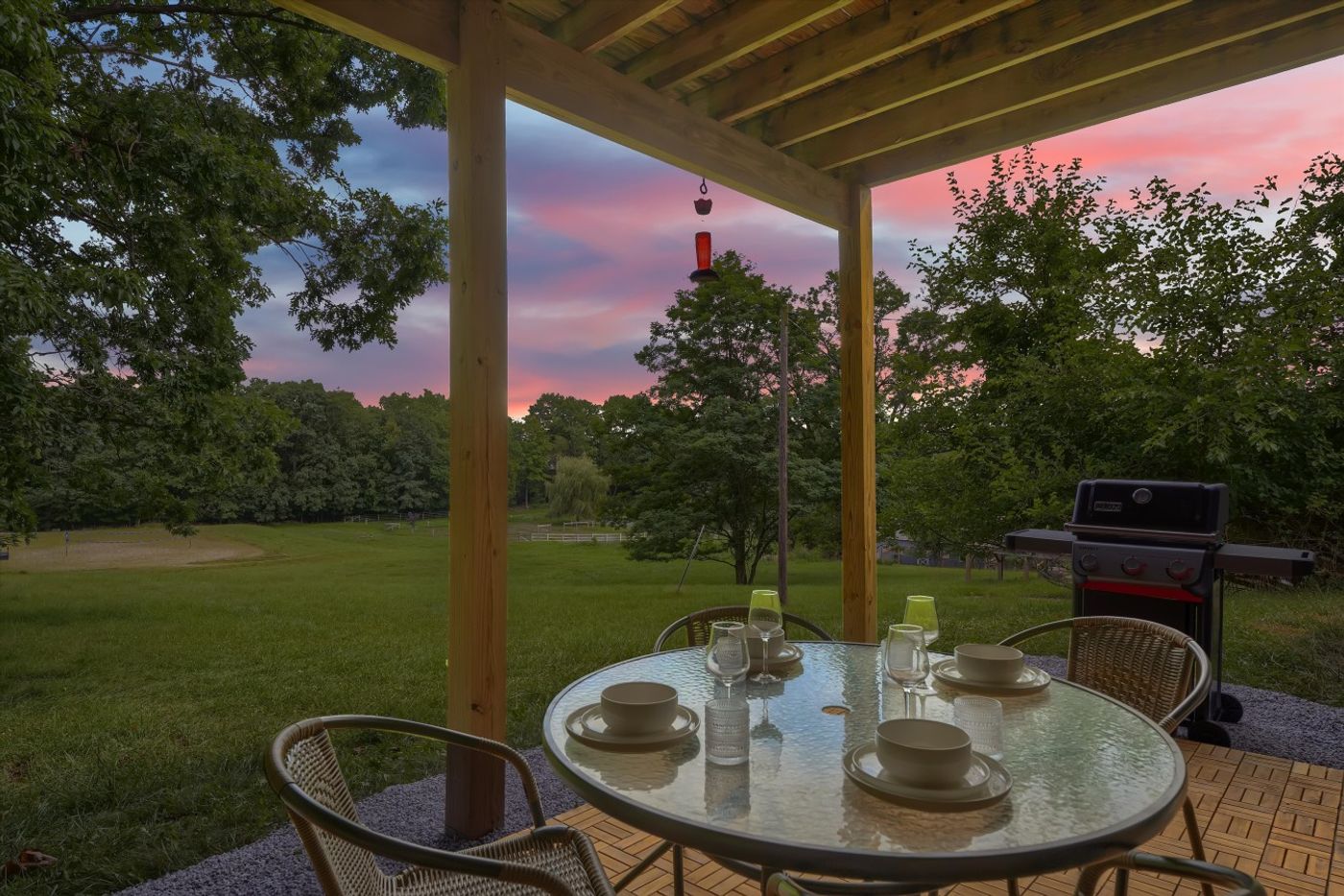 Pergola patio with a round table and chairs at sunset