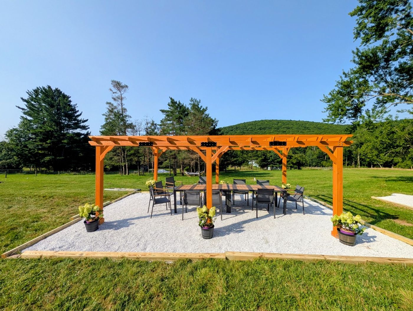 Cedar pergola on a stone patio beside the lawn