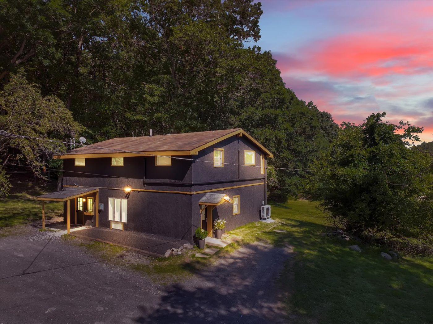The house lit up at twilight among the trees