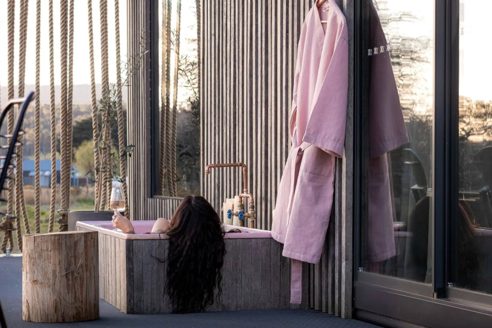 The pink cast iron outdoor bath is equipped with hot and cold water, allowing you to enjoy a relaxing soak year-round.