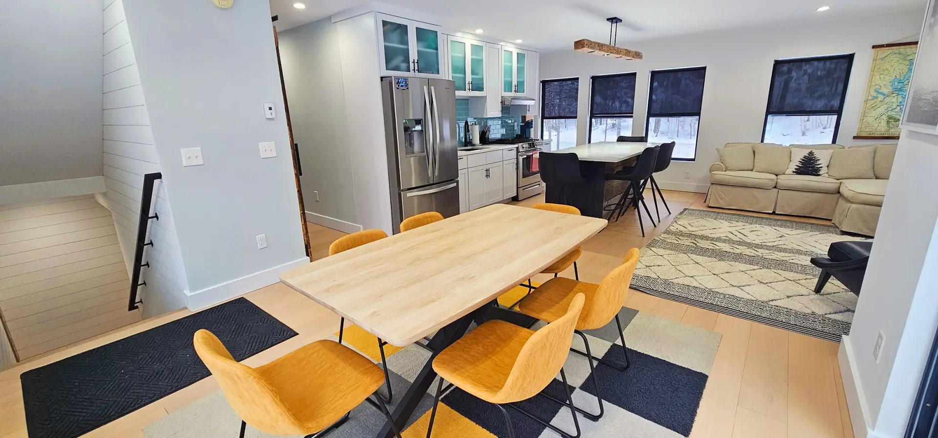 Bright open-concept living space featuring a modern kitchen, large dining table, spacious island seating, and a comfortable lounge area perfect for gathering with family and friends.