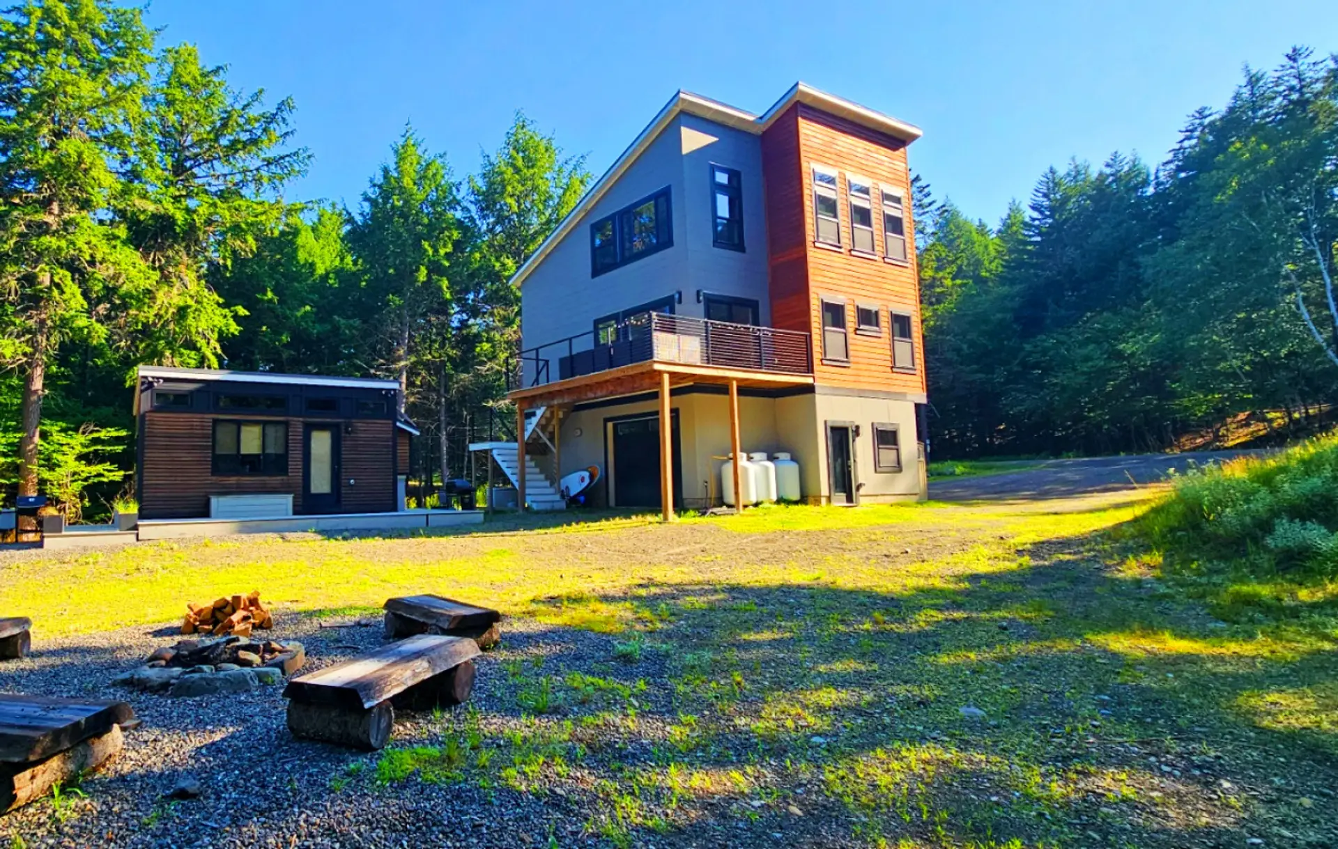 Modern woodland retreat with a spacious deck, private fire pit, and separate guest cabin, surrounded by peaceful forest views and outdoor adventure.
