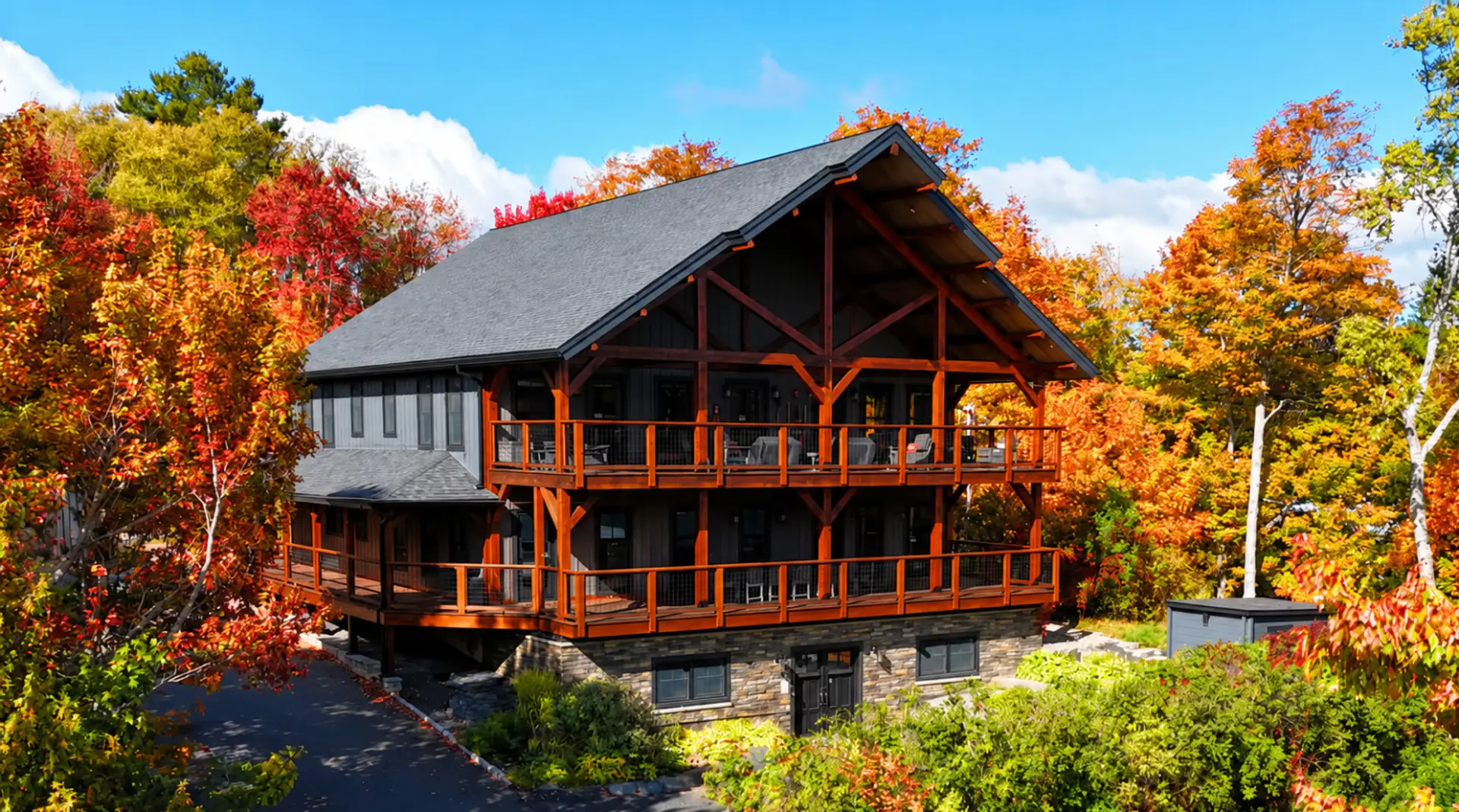 Stunning luxury cabin surrounded by vibrant fall foliage, featuring expansive covered decks, mountain views, and the perfect setting for a memorable Maine getaway.