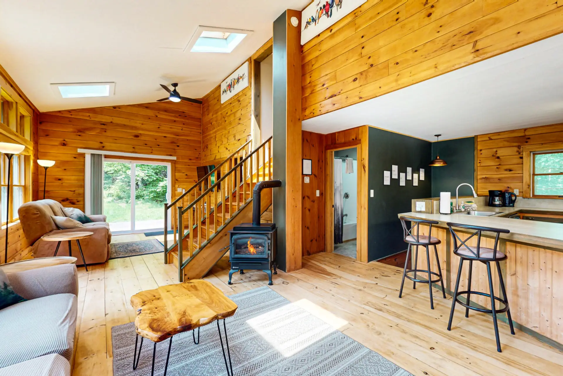 Open-concept cabin interior with a cozy wood stove, vaulted ceilings, and a fully equipped kitchen for relaxing mountain getaways.