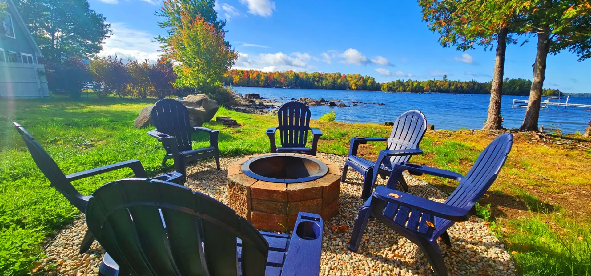 Waterfront fire pit with Adirondack chairs, lake views, and the perfect spot to relax by the water.