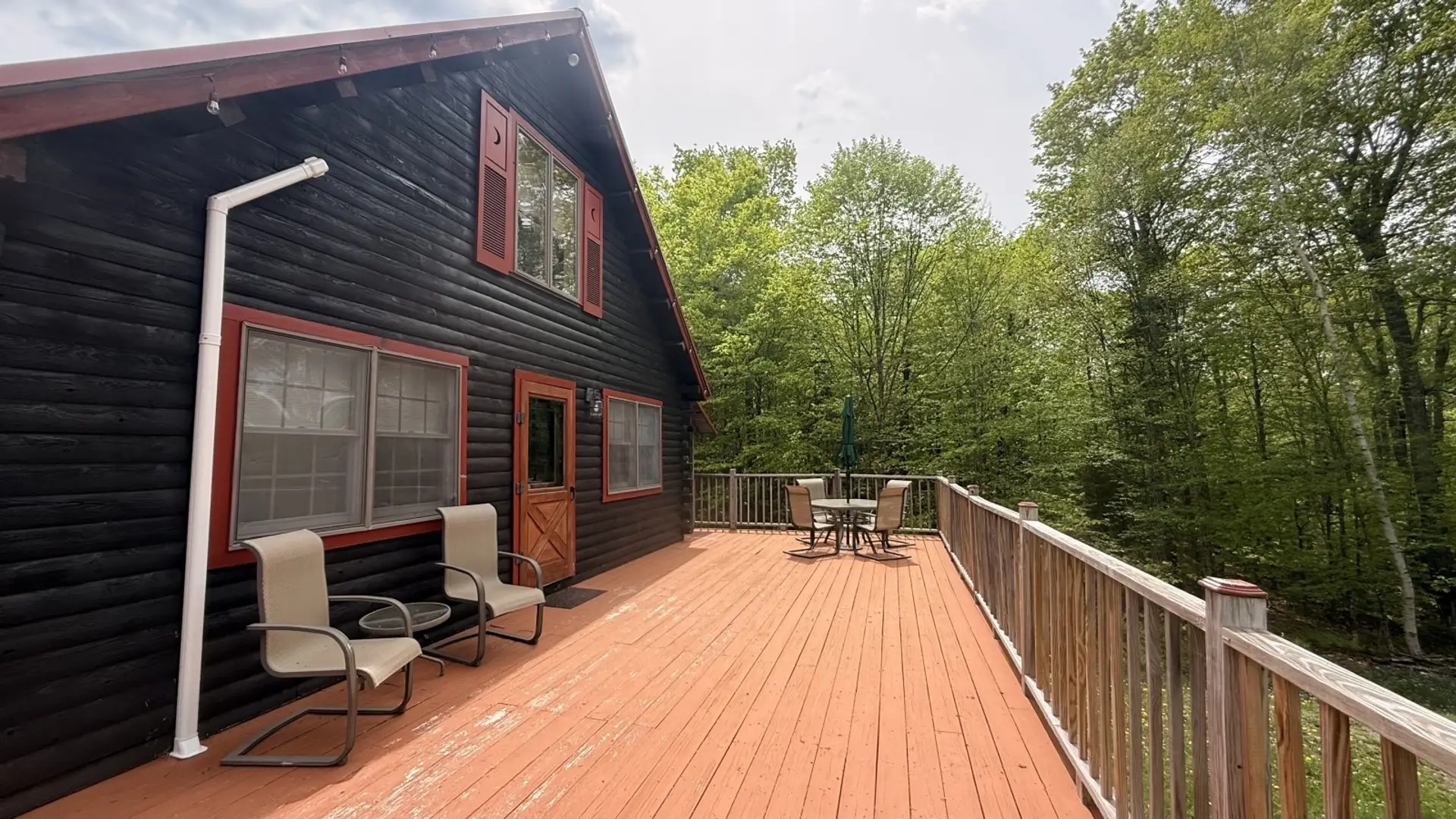 Spacious wraparound deck with outdoor seating, peaceful forest views, and the perfect setting for relaxing cabin getaways.
