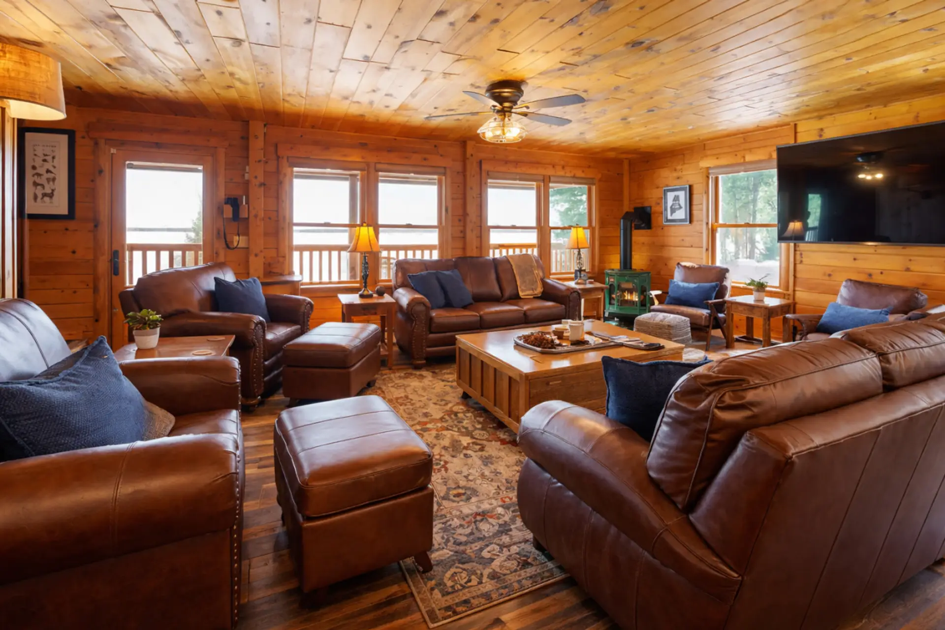 Spacious lakeside cabin living room with leather seating, wood interiors, and relaxing water views.