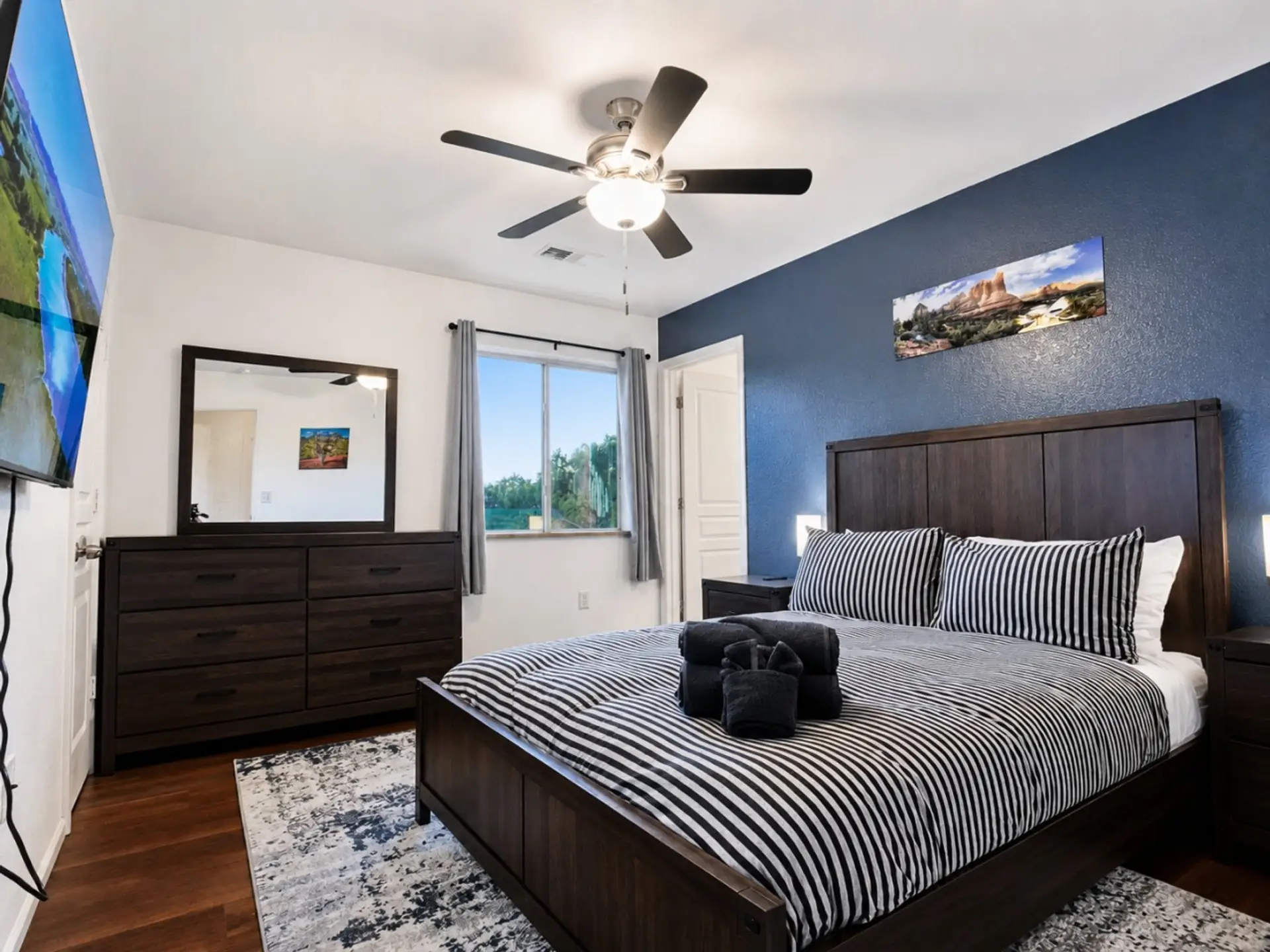Primary suite with dresser storage, ceiling fan, and TV for relaxed evenings.