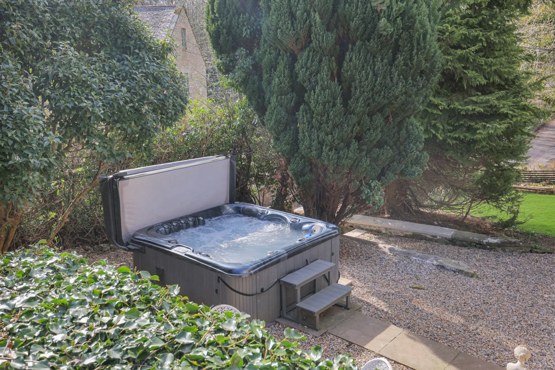 Private hot tub set among mature greenery in the garden
