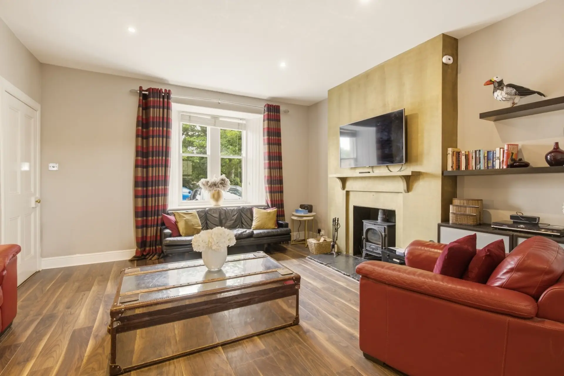 Living room with red leather sofas, wood-burning stove and TV