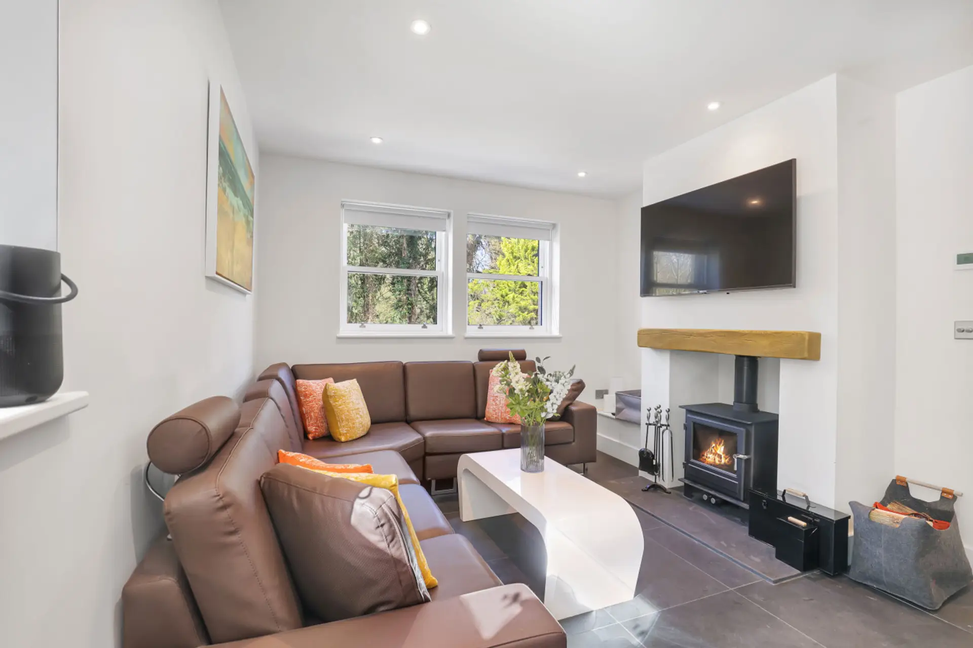 Living area with corner sofa, log burner and wall-mounted TV