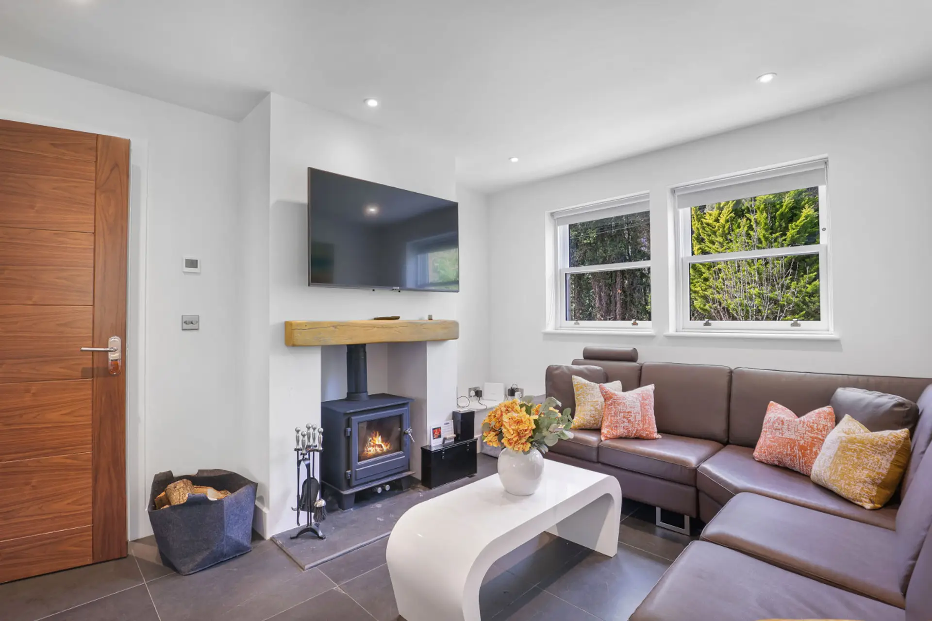 Living area with corner sofa, log burner and wall-mounted TV