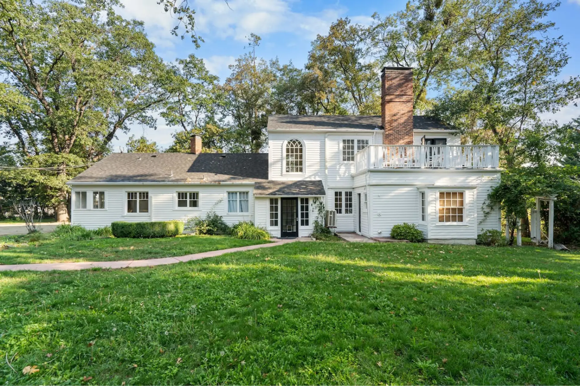 Picturesque farm house invokes nostalgia as if it came from another world. Lush grounds surround this property giving it a secluded feeling far away from daily worries. This is a view from the backyard toward the back of the house