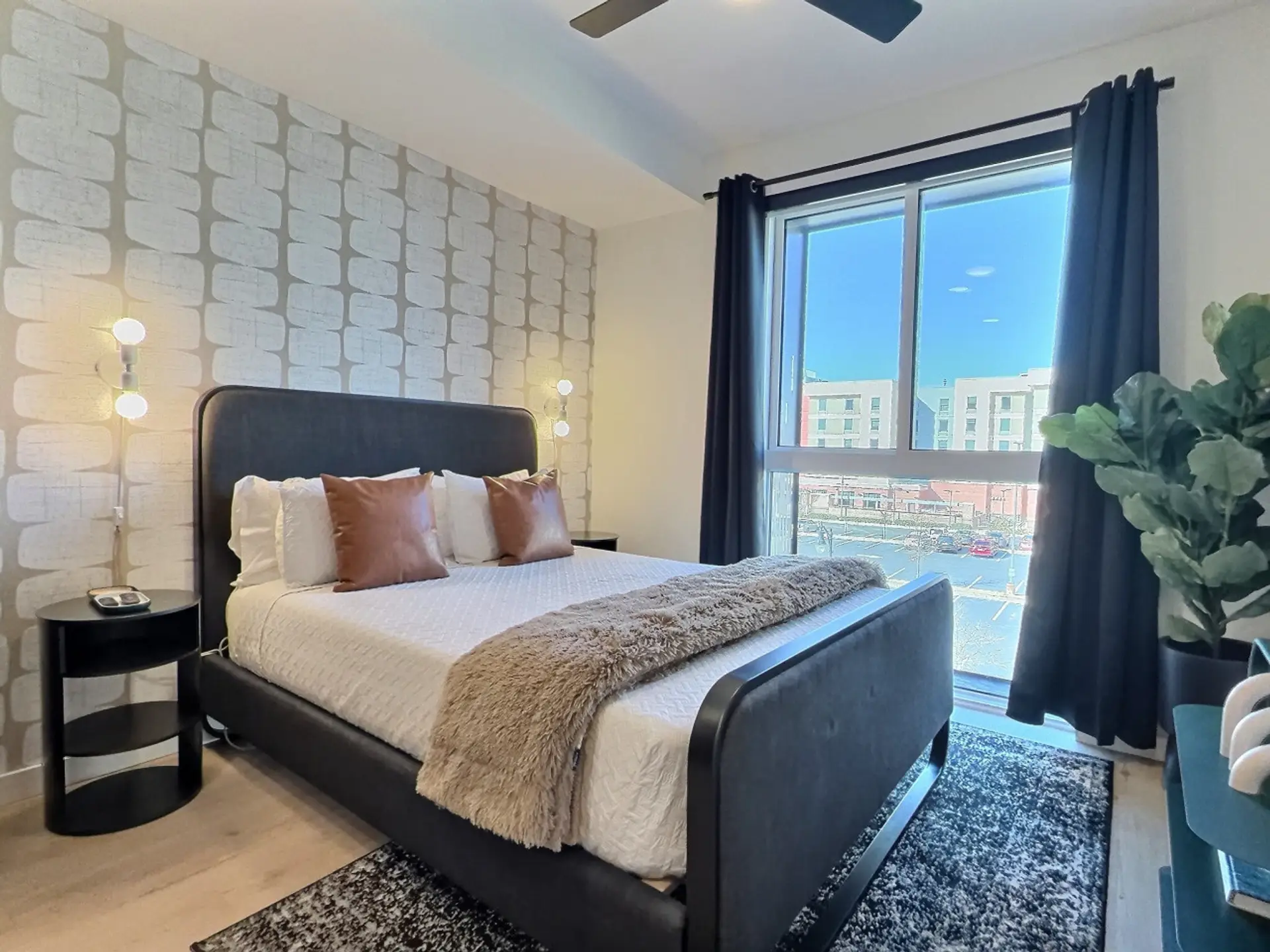 Relax in a cozy bedroom with city views inside a furnished apartment..