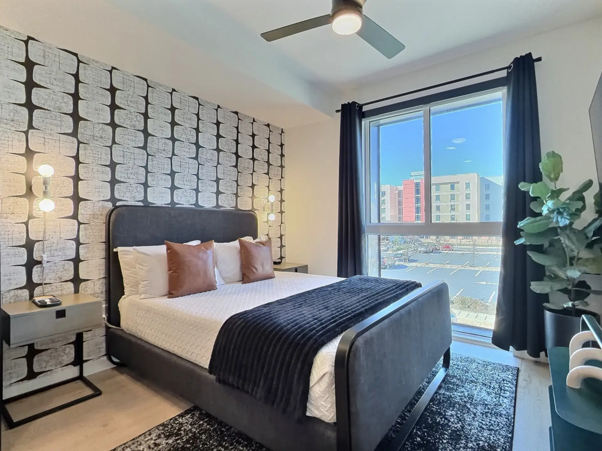 Relax in a cozy bedroom with city views inside a furnished apartment..