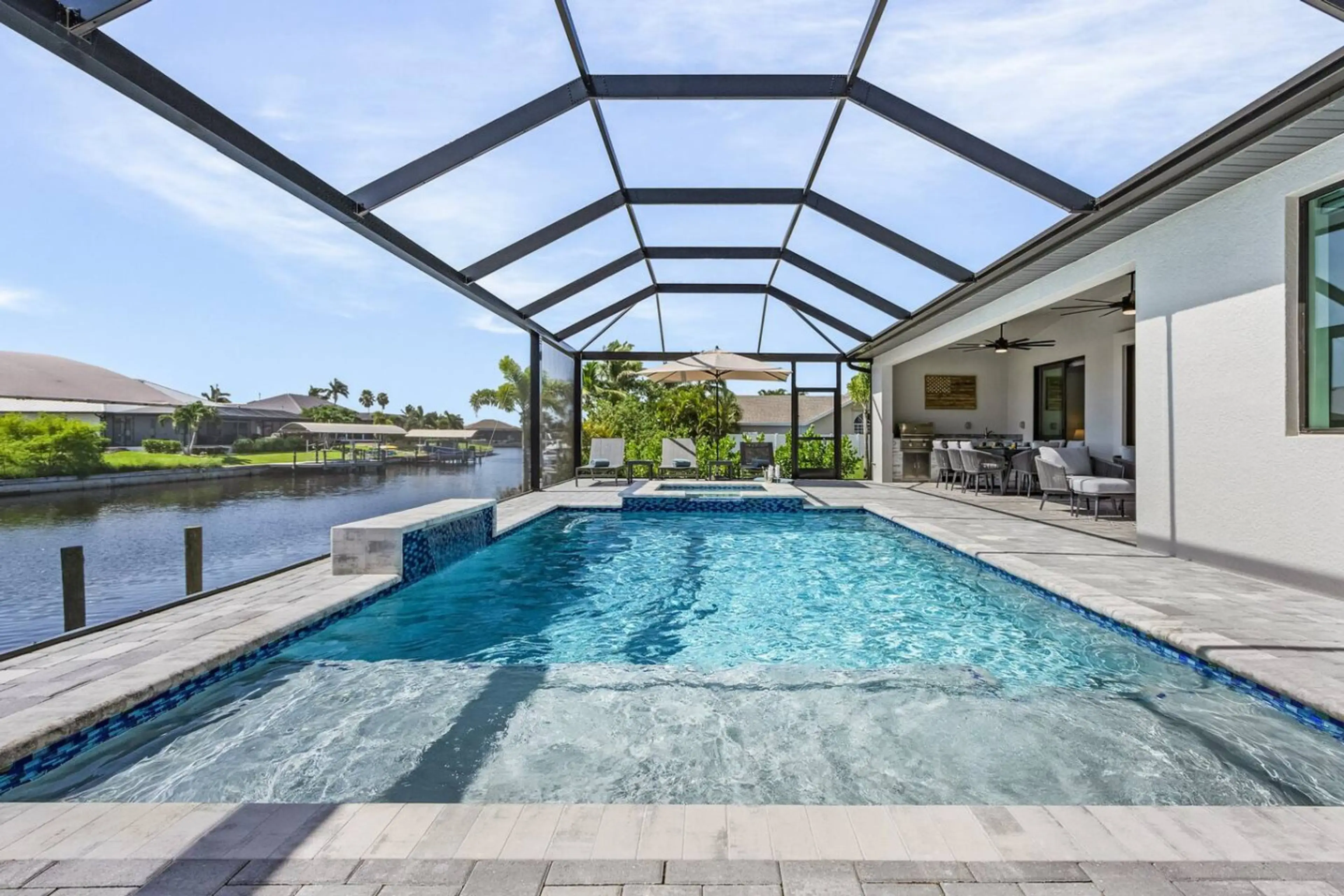 Spacious screened pool area with plenty of seating and a serene canal backdrop.