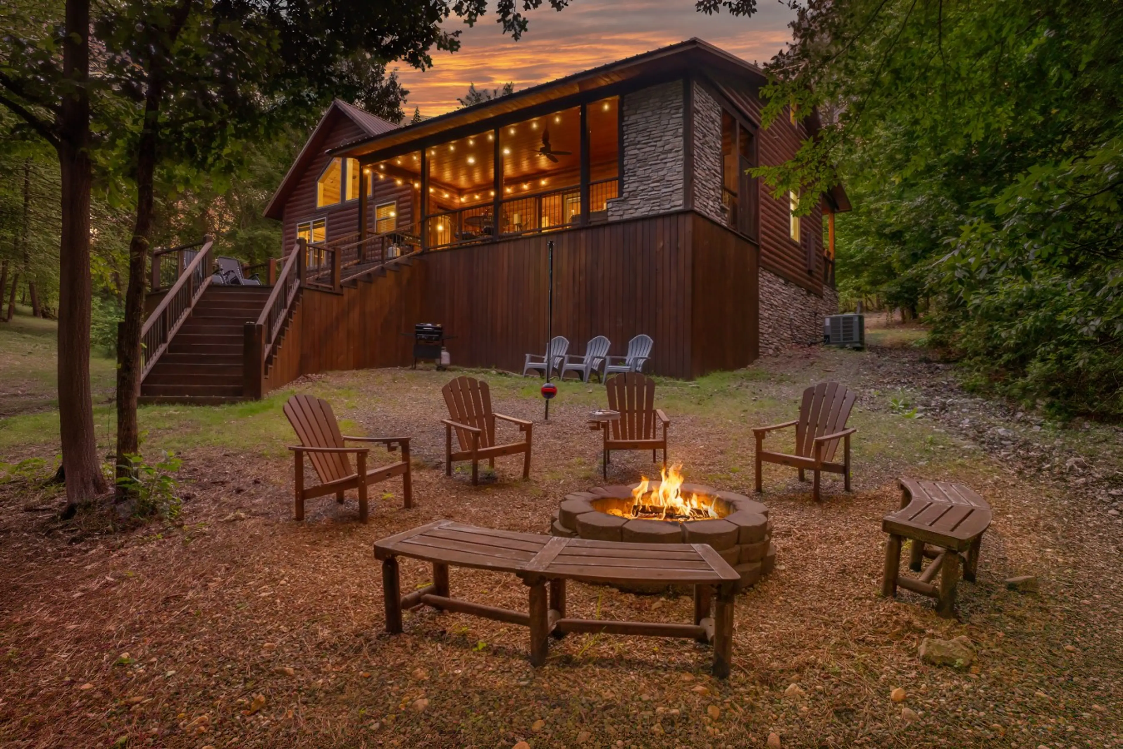 Dusk exterior — fire pit, Adirondack chairs, and illuminated upper deck