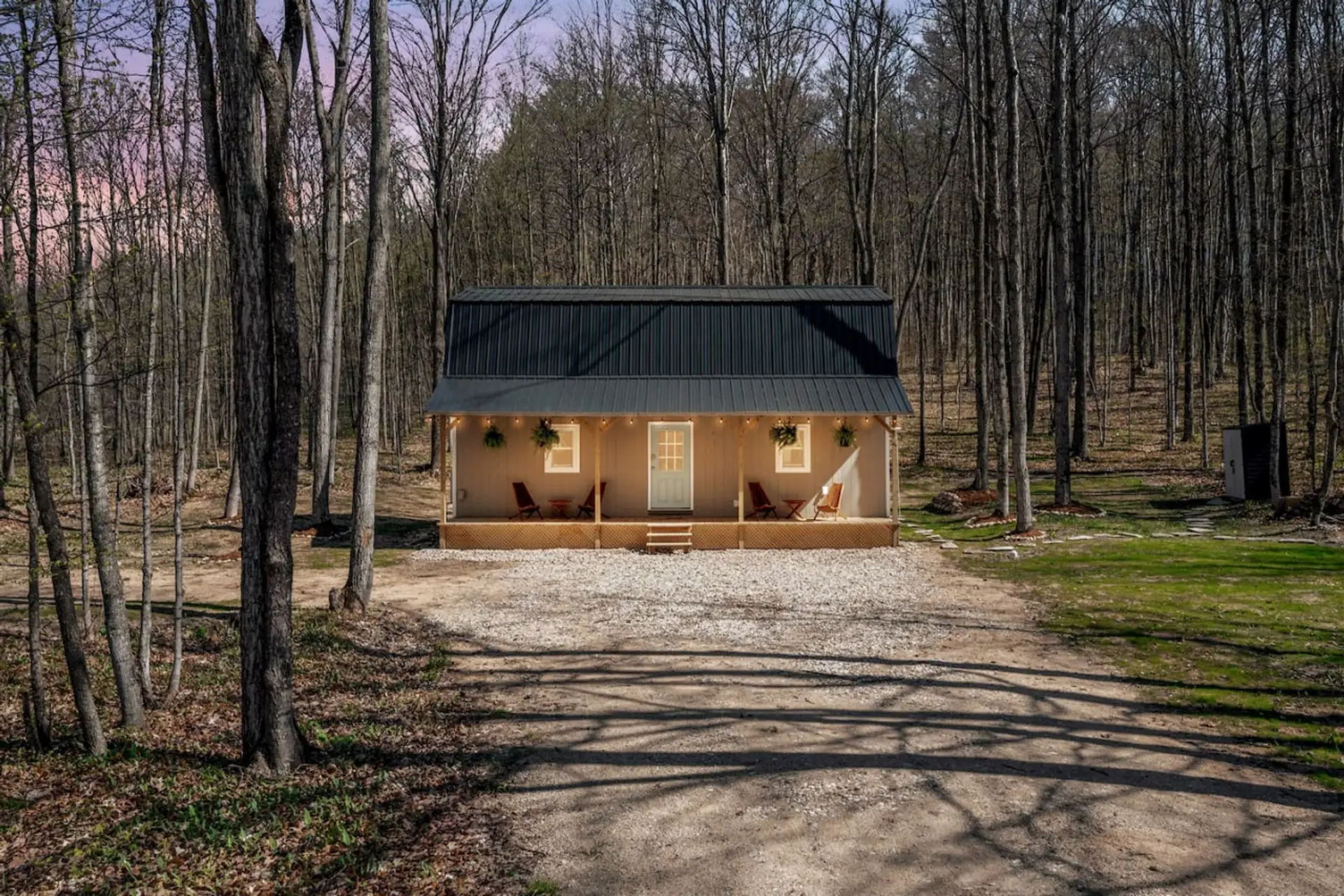 The Hygge Bungalow at Dusk situated between trees on all sides - a quiet and cozy place to unwind.