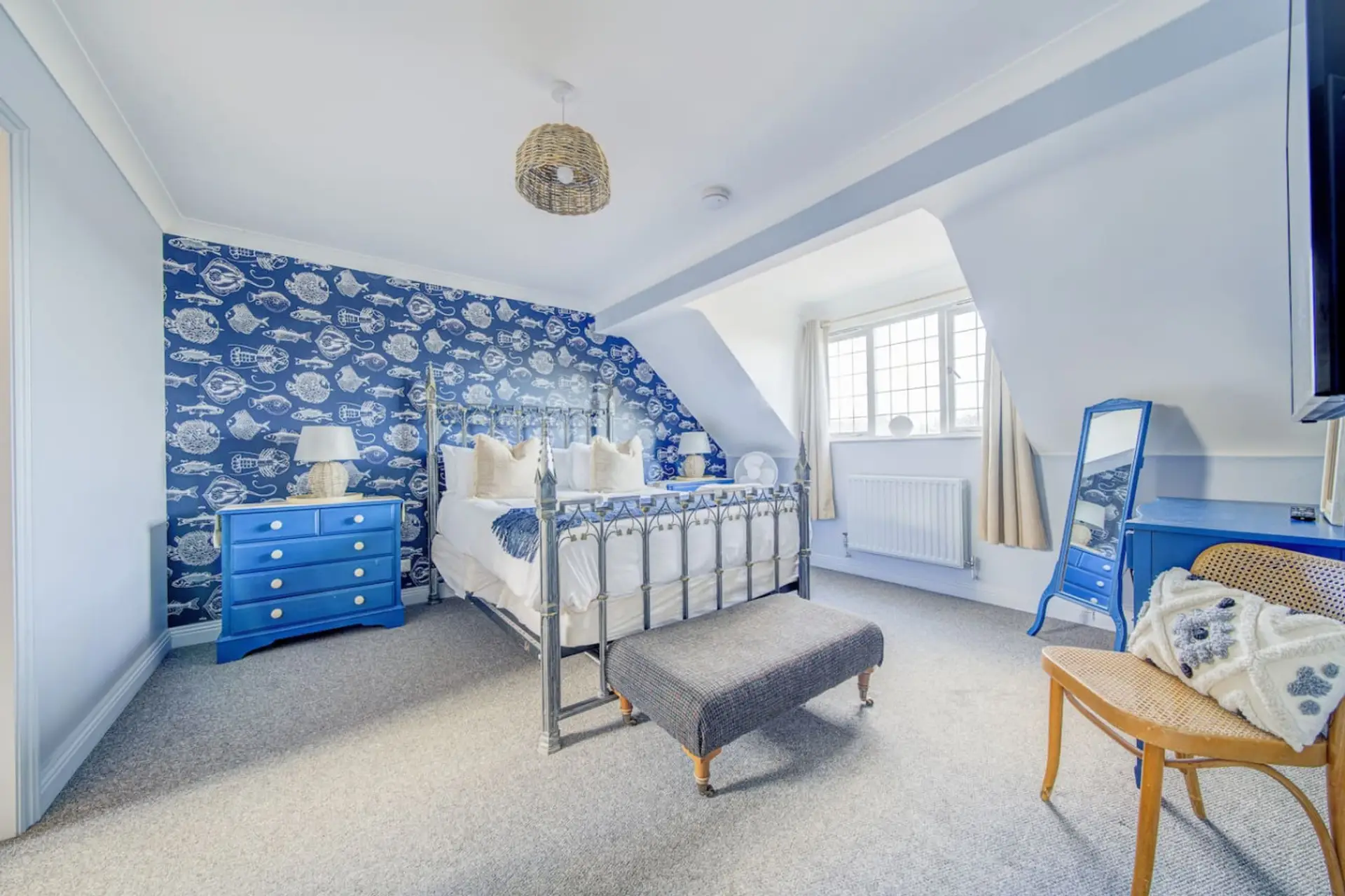 A king four-poster beneath bold nautical wallpaper steals the show.