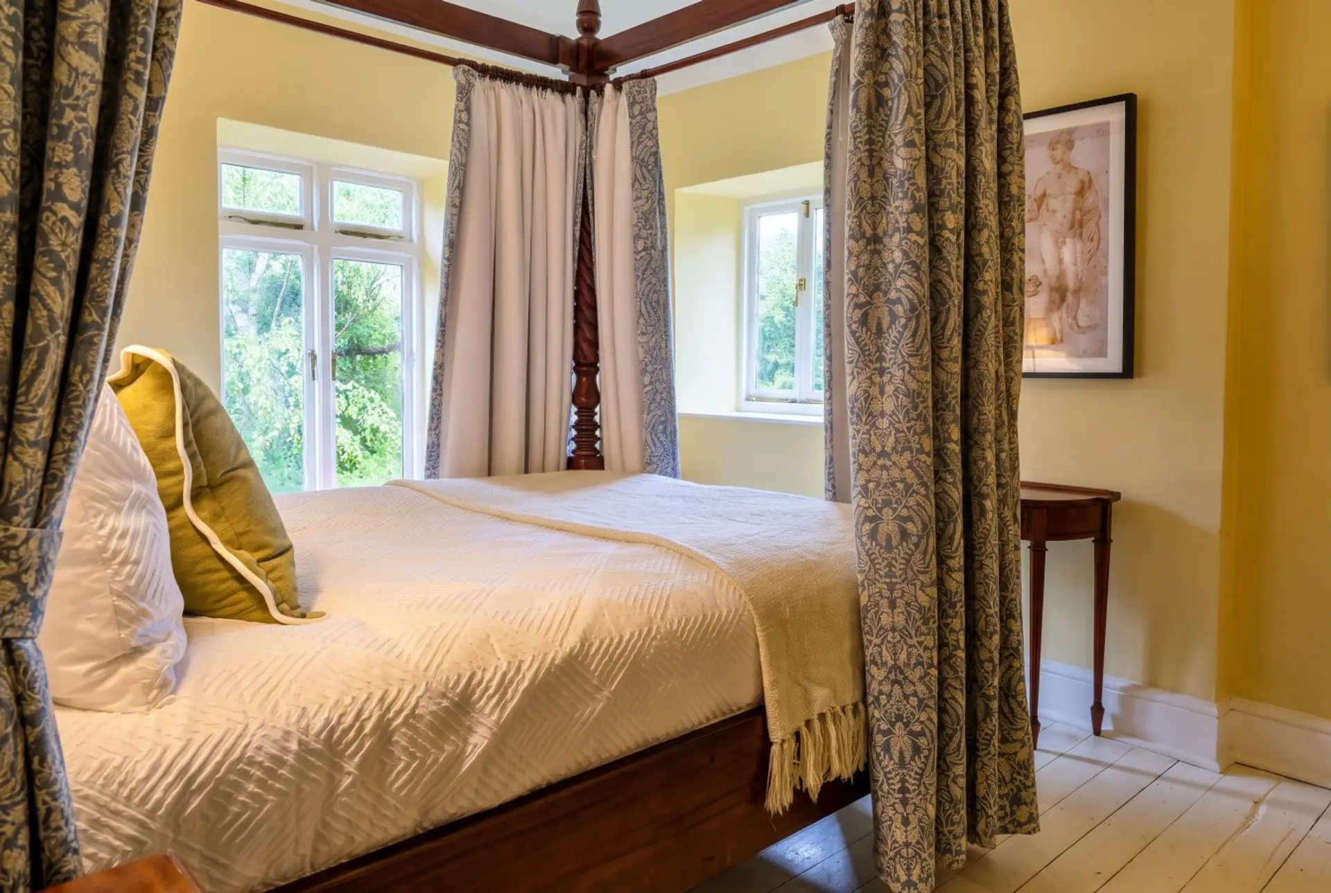 The four-poster room looks out over leafy garden views from twin windows.