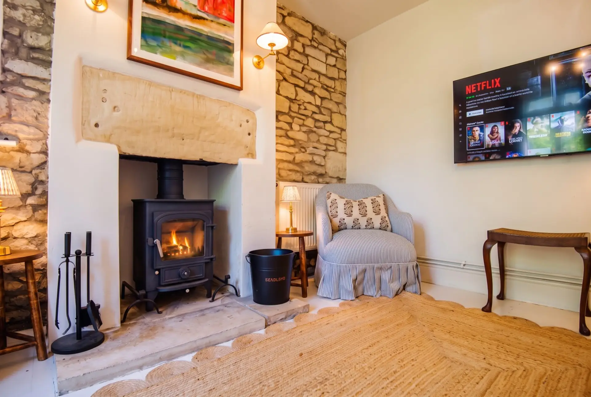 The wood burner and Netflix sit against original stone walls in the snug lounge.
